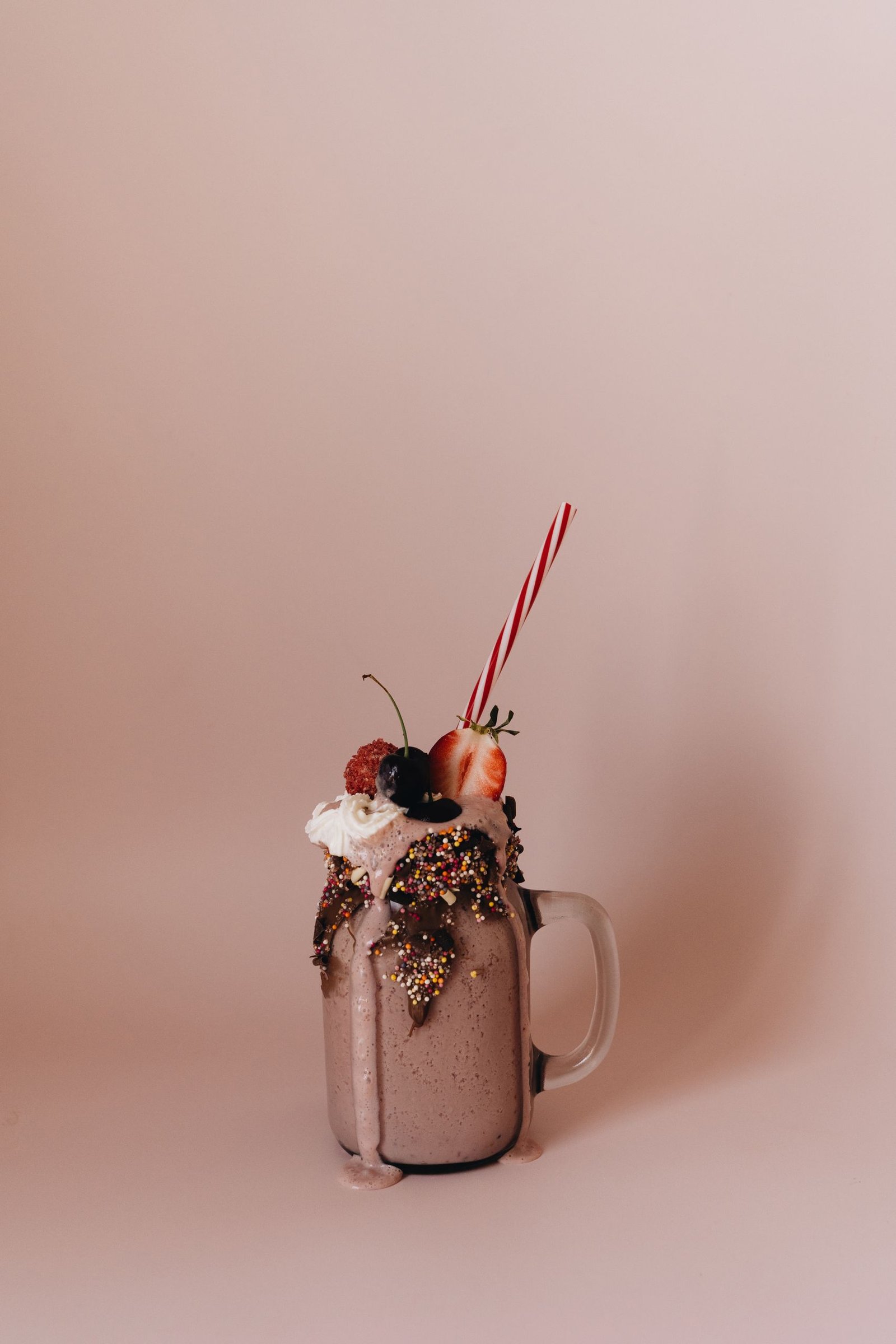 Rich chocolate milkshake topped with whipped cream, berries, and candy straw.
